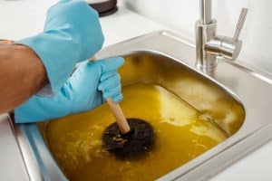 plumber using plunger in a clogged sink