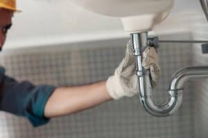 Handyman is repairing faucet of a sink at bathroom. Maintenance and household assistance concept