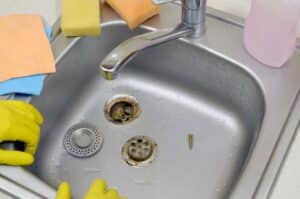 Silvery kitchen sink with a disassembled protective filter. Kitchen sink repair process