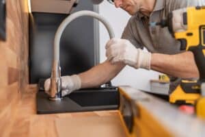 Professional Plumber Installing Kitchen Sink and a Faucet